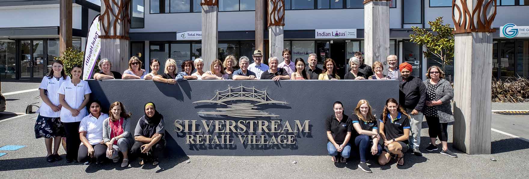 staff from Silverstream retail village shops standing by the village sign