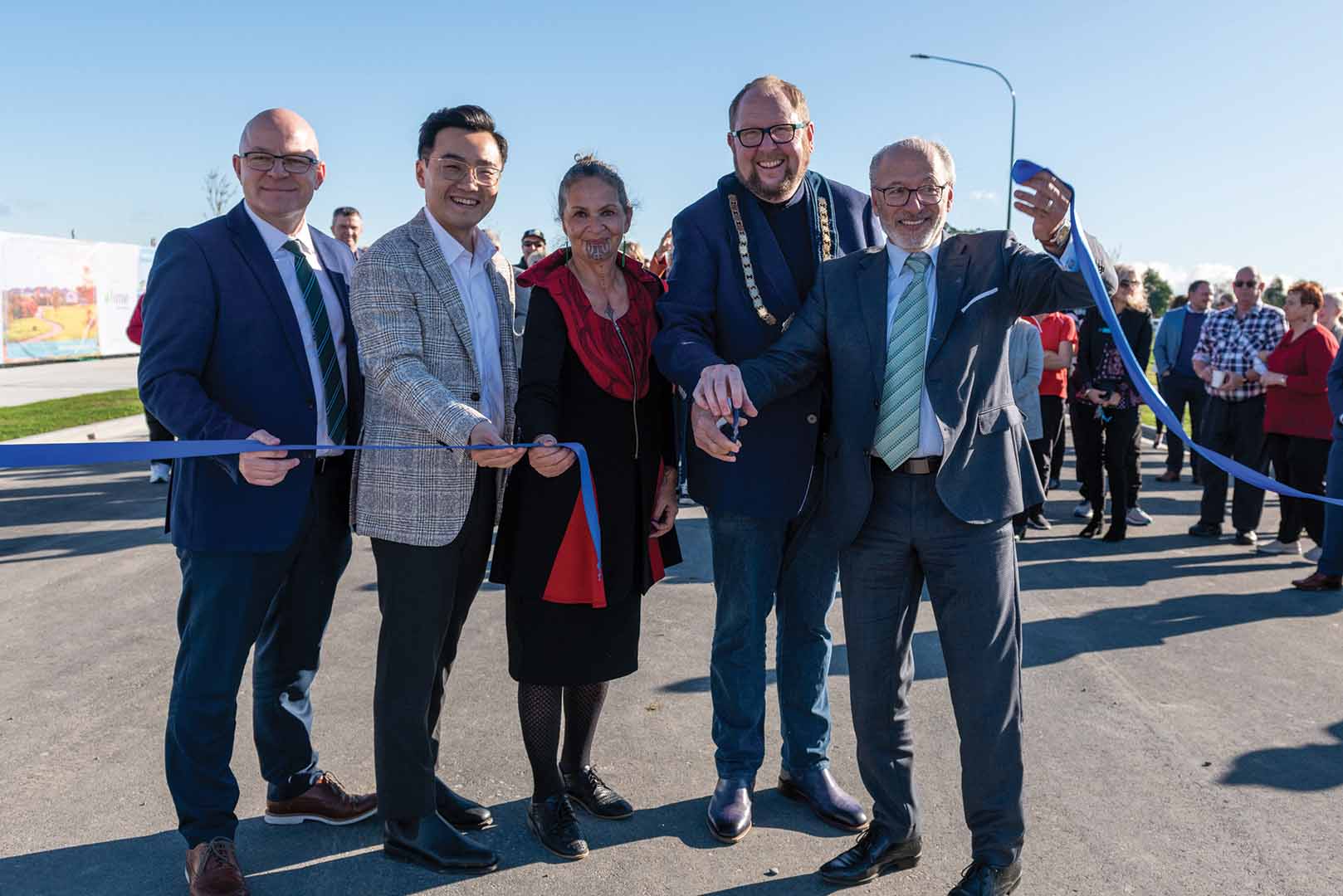 five people hold the ribbon after the ribbon cutting ceremony