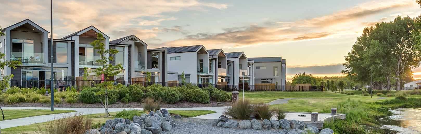 a row of villas facing a river with walking track